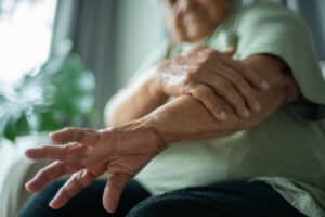 Older adult holding their forearm while experiencing arm weakness and discomfort associated with cervical radiculopathy.