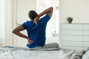 Man sitting on bed with lower back pain