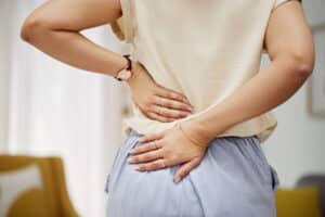 Woman holding her lower back while experiencing pain related to a herniated disc.