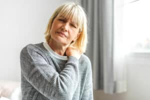Woman holding her neck in discomfort, representing neck pain that may be caused by a pinched nerve.